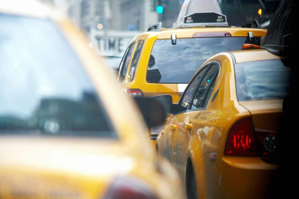 A bright yellow taxi cab parked on a city street, ready to pick up passengers.
