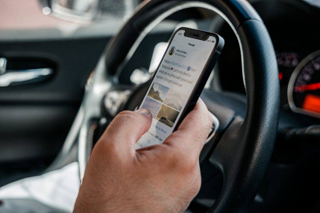 A man driving a car in Houston, distracted by his smartphone while behind the wheel.