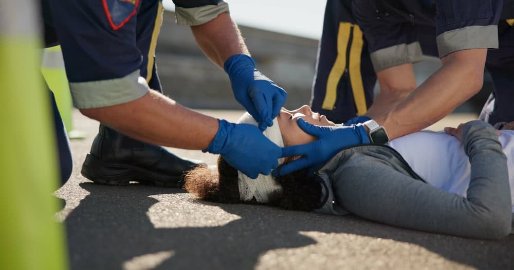 A paramedic assists a woman in standing up after an incident, providing support and care.