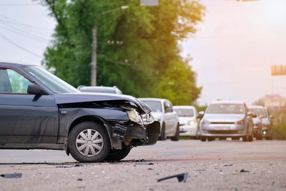 A damaged car from an accident, showing crumpled metal and shattered glass on the driver's side.