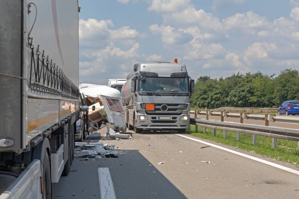 A truck driving down the road, involved in an accident, with debris scattered around.